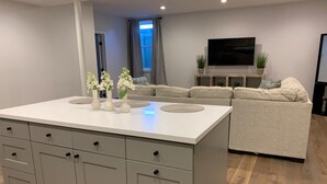 Una sala de estar moderna con una isla central, sofá y televisor de pantalla plana.