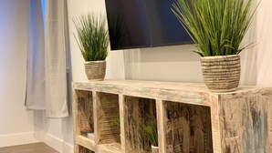 Una consola de madera rústica con dos plantas en macetas y un televisor de pantalla plana montado en la pared.