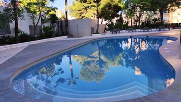 Una piscina al aire libre, sillones reclinables de piscina