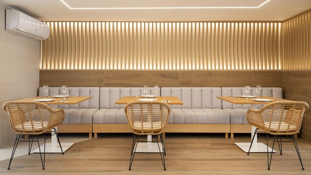 Een modern interieur met een bank, twee eettafels en rieten stoelen.