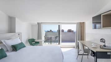 Une chambre d’hôtel équipée d’un lit, d’un bureau, d’une chaise, d’une table et d’un balcon avec vue.