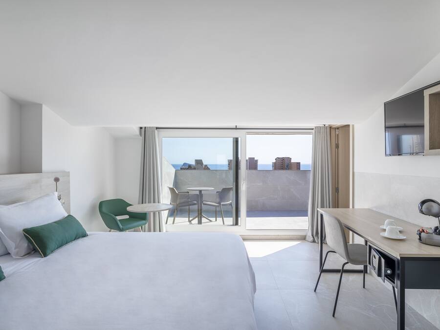 Une chambre d’hôtel équipée d’un lit, d’un bureau, d’une chaise, d’une table et d’un balcon avec vue.