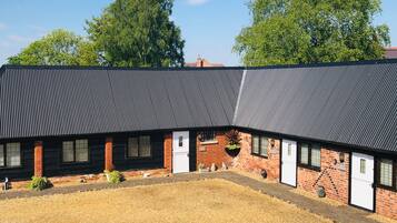 A building with a corrugated metal roof, brick walls, and a gravel courtyard.