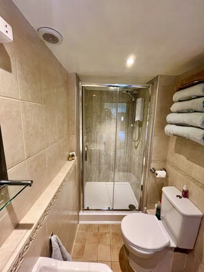A modern bathroom with a glass-enclosed shower, a toilet, and a glass bathtub.