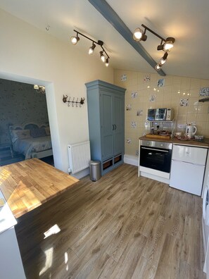 A modern kitchen with wooden flooring, a blue cabinet, a white refrigerator, and a microwave.