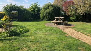 A well-maintained garden with a wooden bench and a circular stone path. - Hunt House Quarters (Rugby)