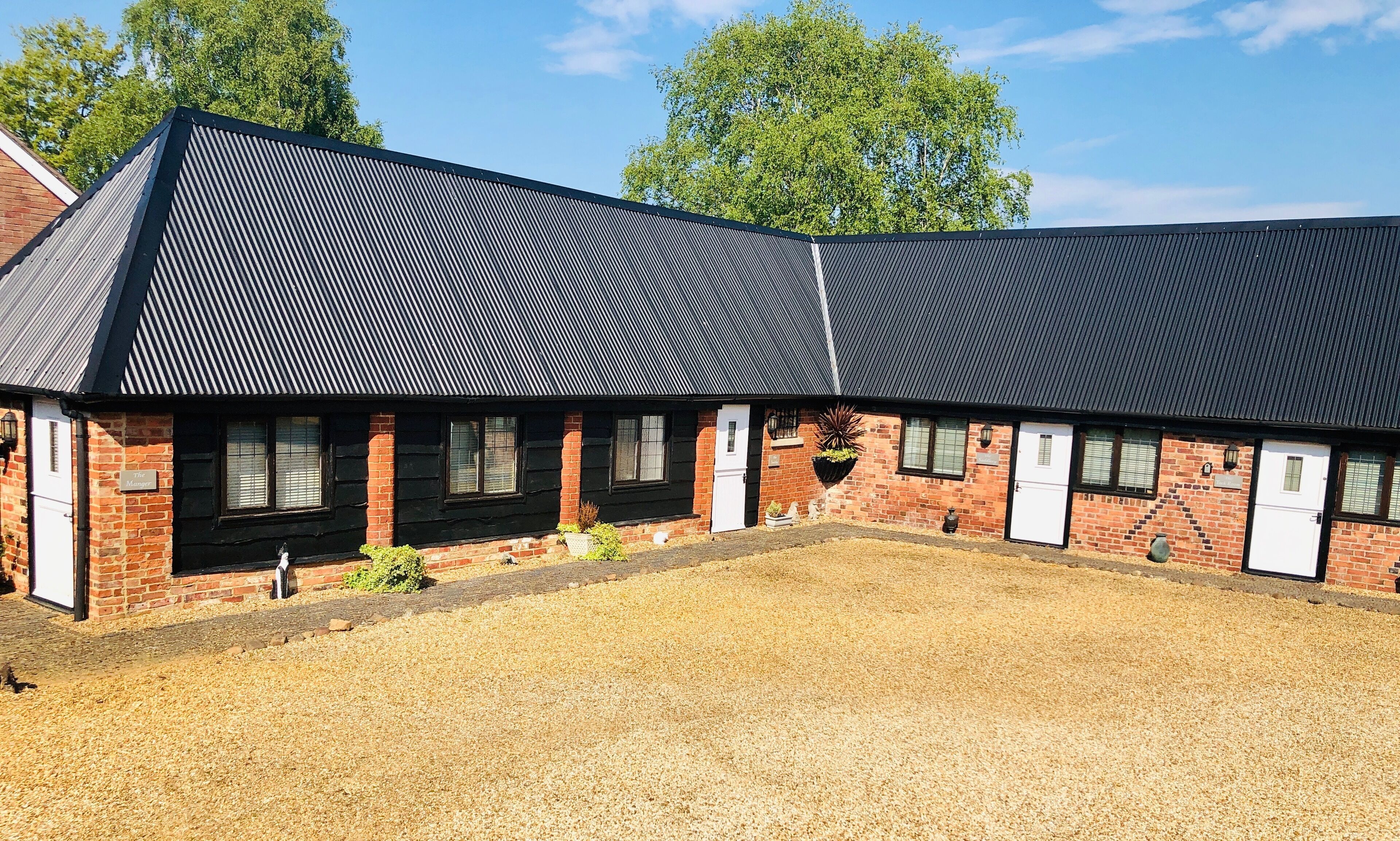 A building with a corrugated metal roof, brick walls, and a gravel driveway.