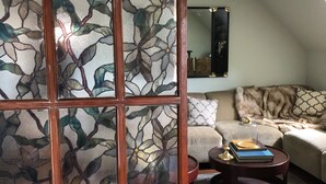 A room with a wooden partition featuring a floral pattern, a sofa, a coffee table, and a mirror on the wall.