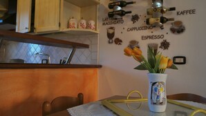 A kitchen with a wall-mounted espresso machine, a coffee cup, and a vase with tulips. - Central Porto San Paolo, 2 bedrooms, 6 beds, Wi-fi, air conditioning (Porto San Paolo)
