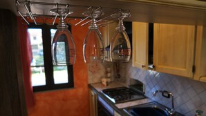 A kitchen with a gas stove, a sink, and hanging wine glasses. - Central Porto San Paolo, 2 bedrooms, 6 beds, Wi-fi, air conditioning (Porto San Paolo)