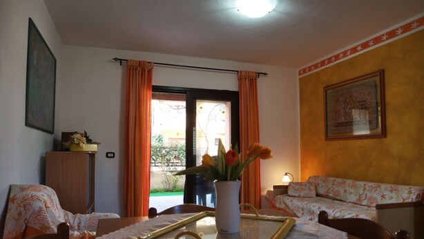 A room with a dining table, chairs, a vase with flowers, a sofa, and a painting on the wall. - Central Porto San Paolo, 2 bedrooms, 6 beds, Wi-fi, air conditioning (Porto San Paolo)