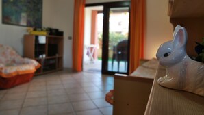 A room with a sofa, a cabinet, and a white rabbit figurine on a table. - Central Porto San Paolo, 2 bedrooms, 6 beds, Wi-fi, air conditioning (Porto San Paolo)
