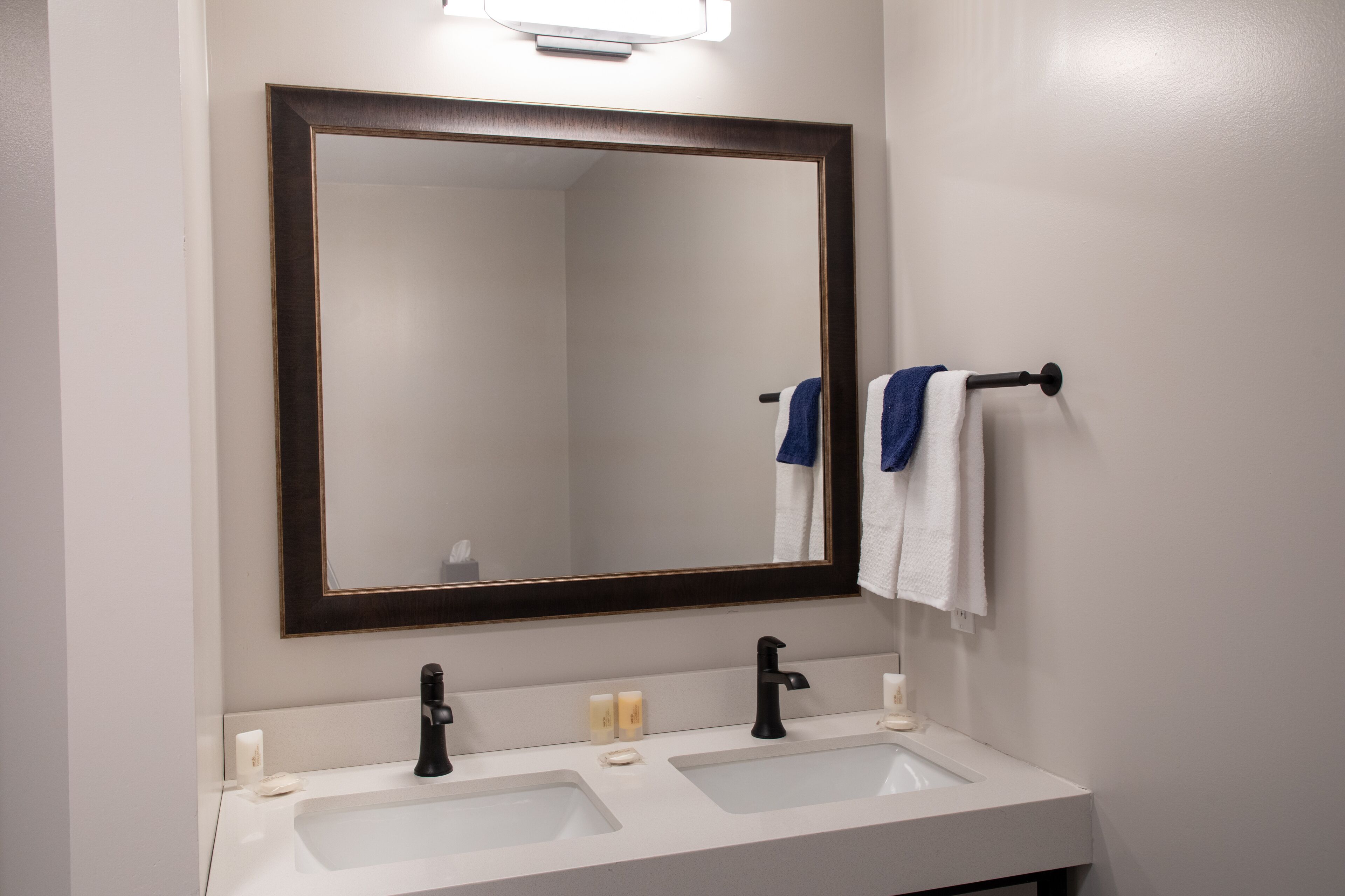 Une salle de bain avec deux lavabos, un grand miroir et un porte-serviettes avec des serviettes.