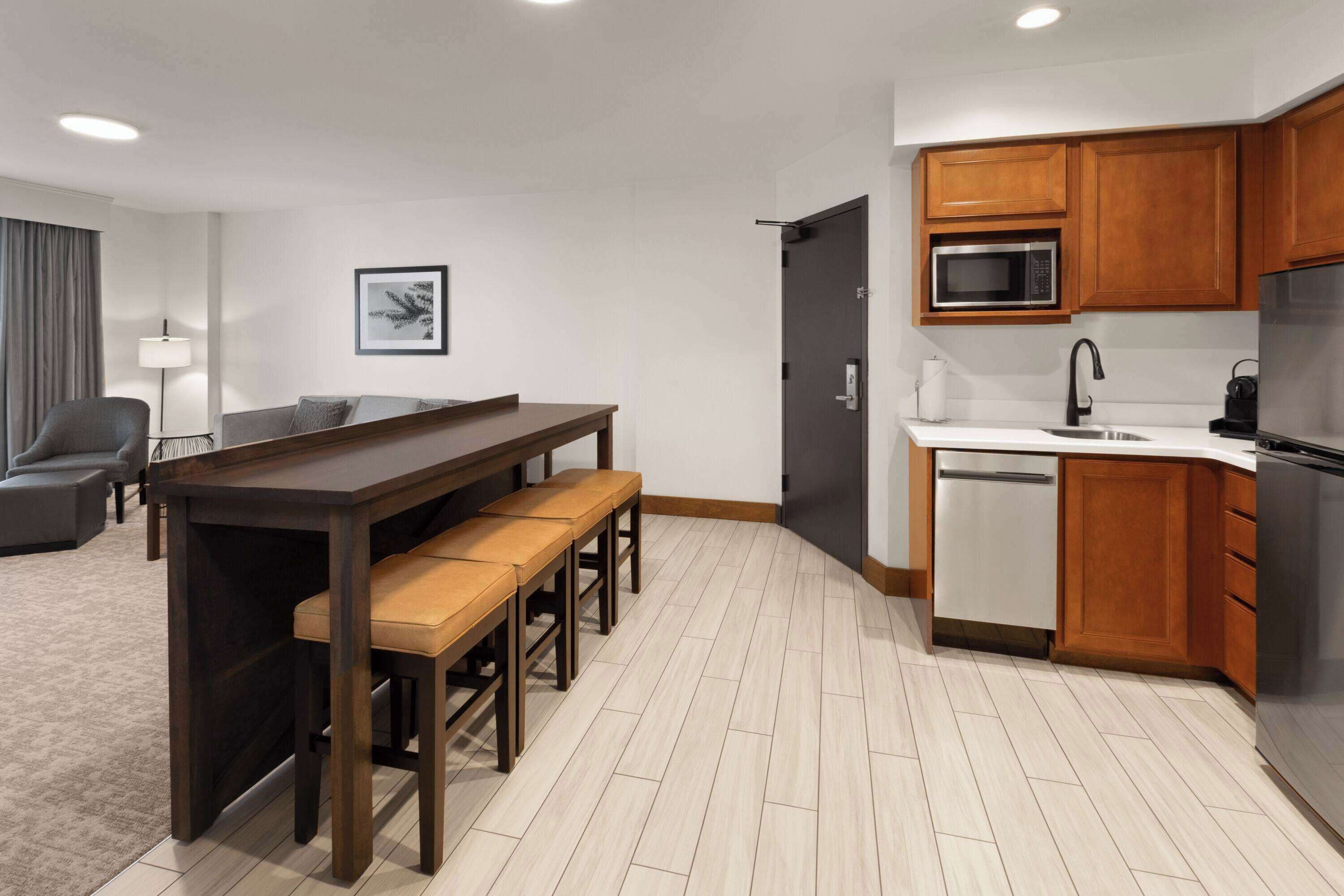 A modern kitchen with wooden cabinets, a built-in microwave, and a stainless steel refrigerator.