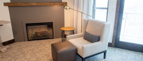 Een moderne woonkamer met een open haard, een bank, een poef en een vloerlamp.