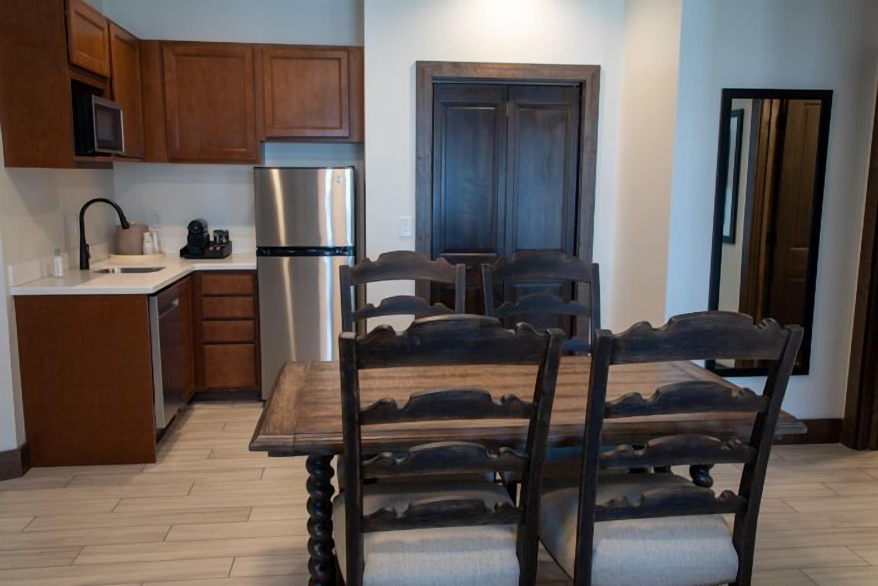 Une cuisine moderne avec des meubles en bois, un réfrigérateur en acier inoxydable et une table à manger avec des chaises.