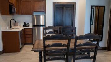 Une cuisine moderne avec des meubles en bois, un réfrigérateur en acier inoxydable et une table à manger avec des chaises.