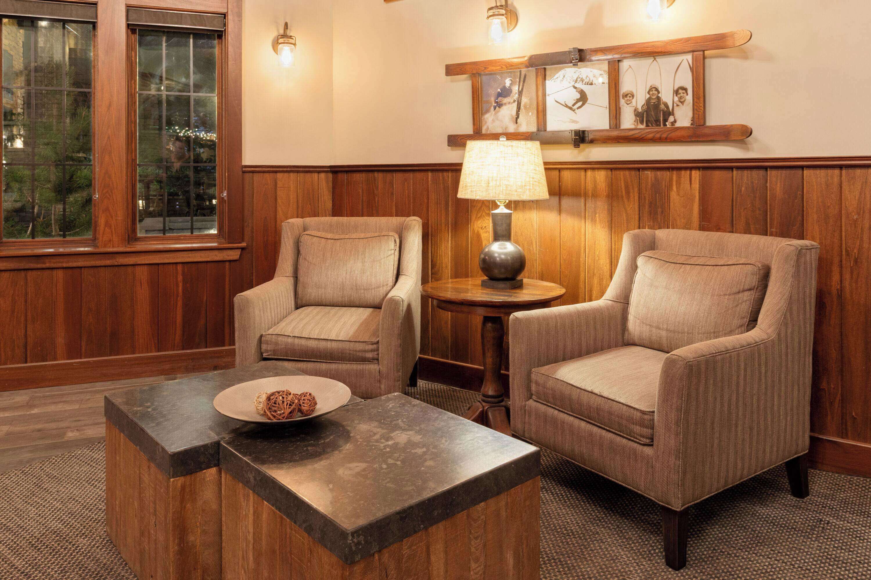 A room with two armchairs, a small round table with a lamp, and a decorative plate on the table.