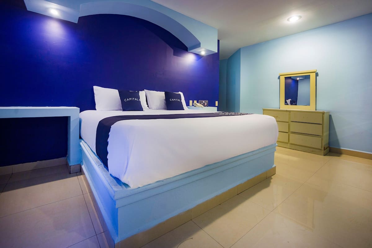 A modern bedroom with a large bed, a dresser, and a mirror.