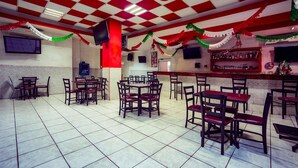 Un restaurante con techo a cuadros rojos y blancos, suelo de baldosas y sillas rojas acolchadas.