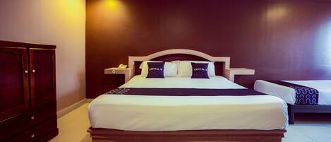 Habitación de hotel con una cama grande, una mesita de noche, un armario y una pared de color oscuro.