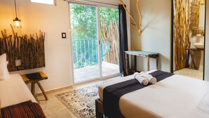 A hotel room with a bed, a small table, a chair, a balcony with a view of greenery, and a decorative wall. -  Straw Hat Tulum (Tulum)