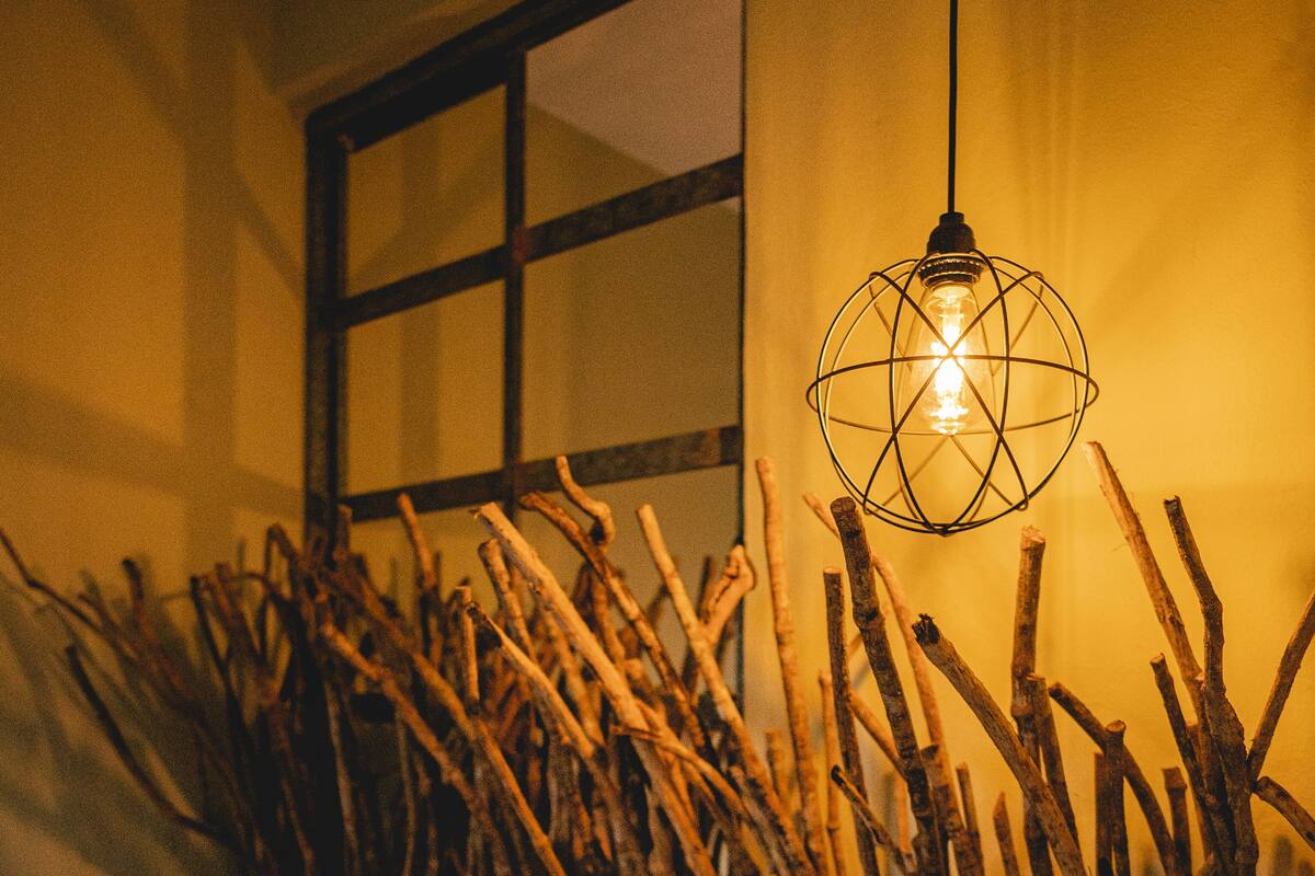 A room with a bed, a hanging light fixture, and a window with blinds.