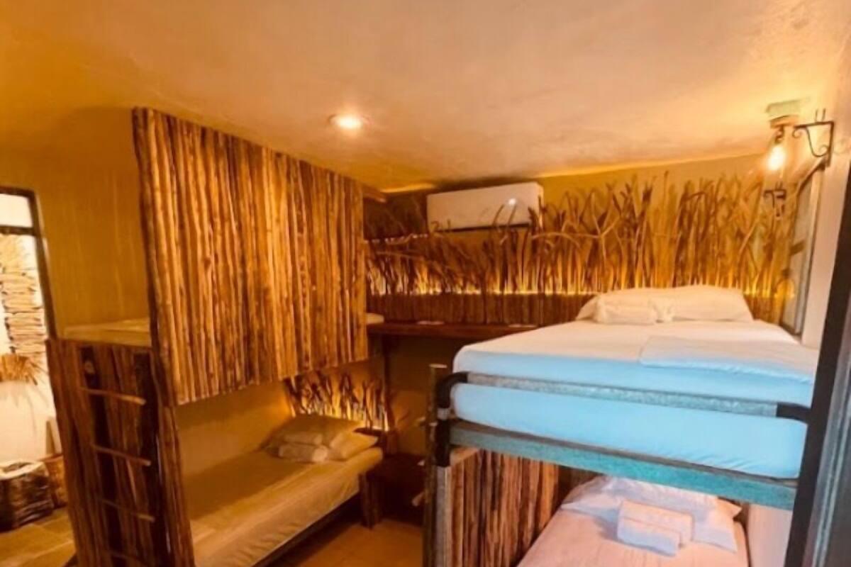 A dormitory room with bunk beds, a wooden wall, and a ceiling fan.