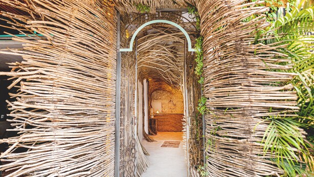 A narrow, covered pathway with a thatched roof, flanked by vertical bamboo structures. -  Straw Hat Tulum (Tulum)