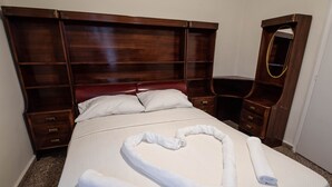 Ein ordentlich bezogenes Bett mit einer herzförmigen Handtuchgestaltung, einem Holzkopfteil und einem Spiegelunterschrank.