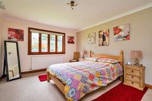 A bedroom with a bed, a mirror, a window, a radiator, and wall decorations. - The Grove Annexe (Craven Arms)