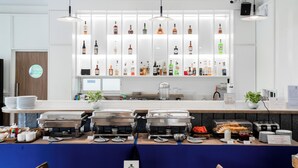 Montaje de bufé con diversas opciones de comida y una barra de bebidas con botellas ordenadas.