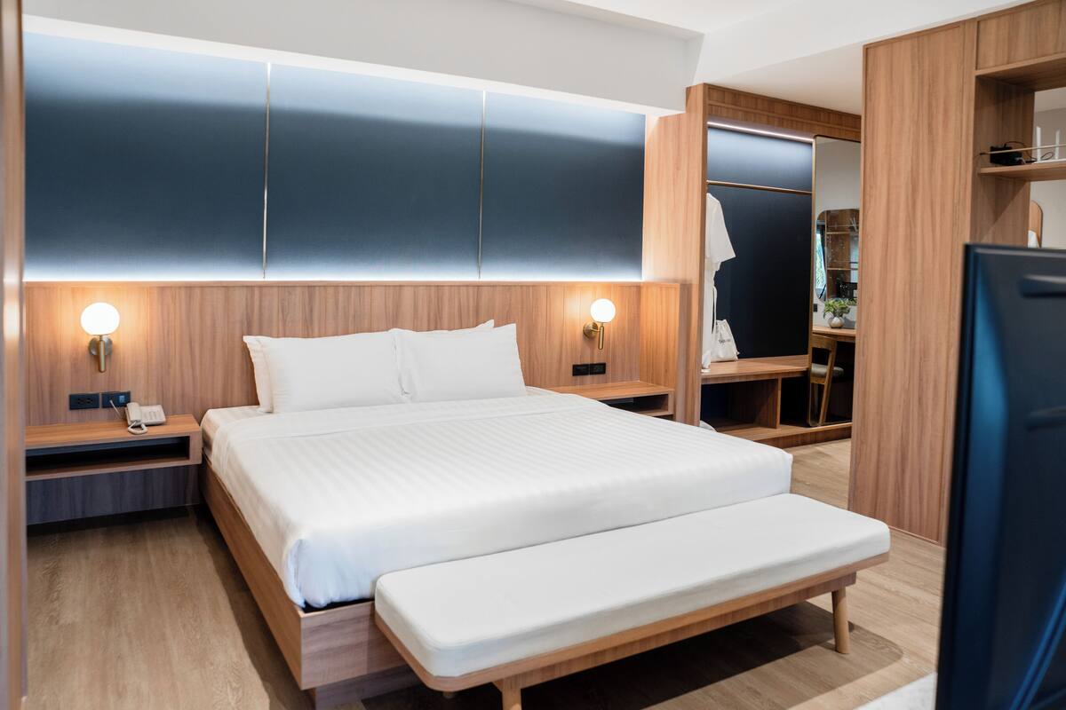 Een moderne hotelkamer met een groot bed, nachtkastjes, een inbouwkast en een televisie.