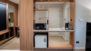 Una cocina compacta con microondas integrado, un refrigerador pequeño y una cafetera sobre una encimera de madera.