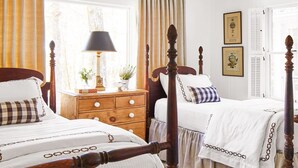 A traditional bedroom with two beds, a ceiling fan, and a wooden dresser.