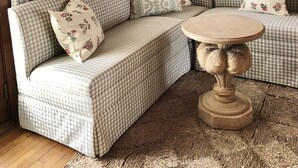 A cozy room with a checkered sofa, a round wooden table, and a wall-mounted lamp.