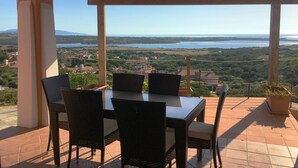 An outdoor patio with a table and chairs, overlooking a scenic landscape with a body of water and hills.