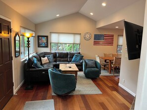 A living room with a sectional sofa, a coffee table, and a dining area with a table and chairs.