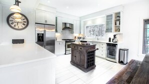 A modern kitchen with white cabinetry, stainless steel appliances, and a central island. - Tremblant Prestige - Panache 632 (Mont-Tremblant)