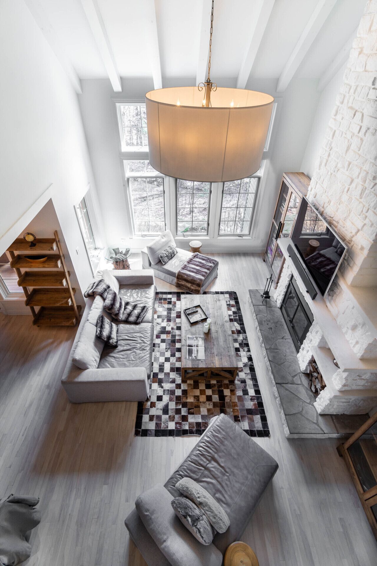 A spacious loft-style living area with a large window, a fireplace, and a modern chandelier.
