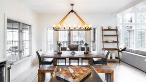 A modern dining area with a large wooden table, benches, and a chandelier. - Tremblant Prestige - Panache 632 (Mont-Tremblant)