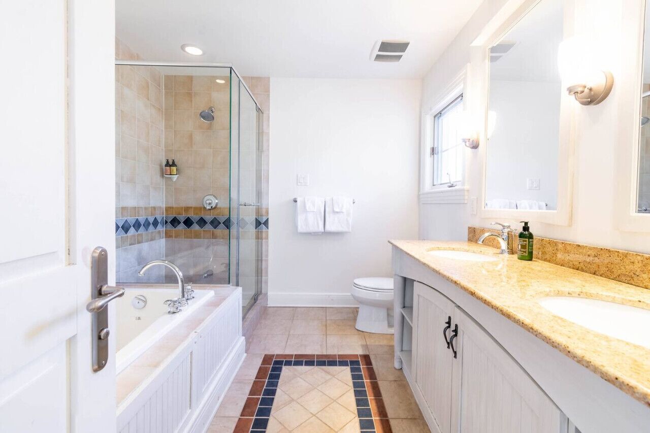 Une salle de bain moderne avec une douche à parois de verre, des toilettes blanches et un meuble-lavabo doté d’un évier et d’un miroir.