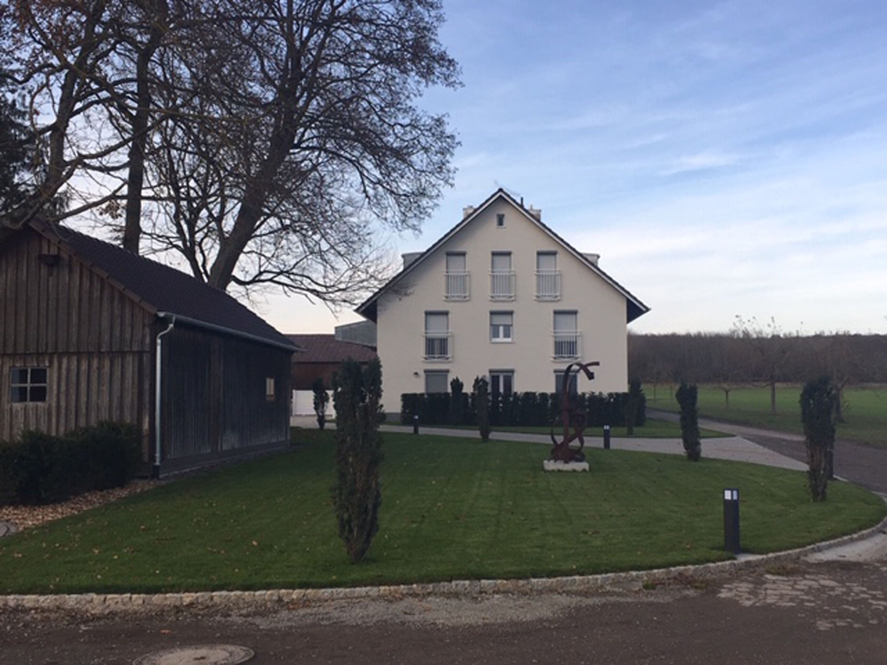 A two-story building with a symmetrical facade, a central entrance, and a well-maintained lawn with a few trees.