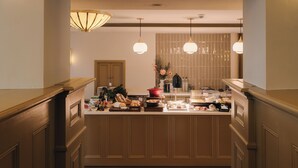 Una cocina con armarios de madera, una encimera con diversos alimentos e iluminación colgante.