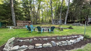 A backyard with a stone border, green chairs, a table, and a shed. - Rustic Lodge near Black Moshannon & Penn State (Philipsburg)