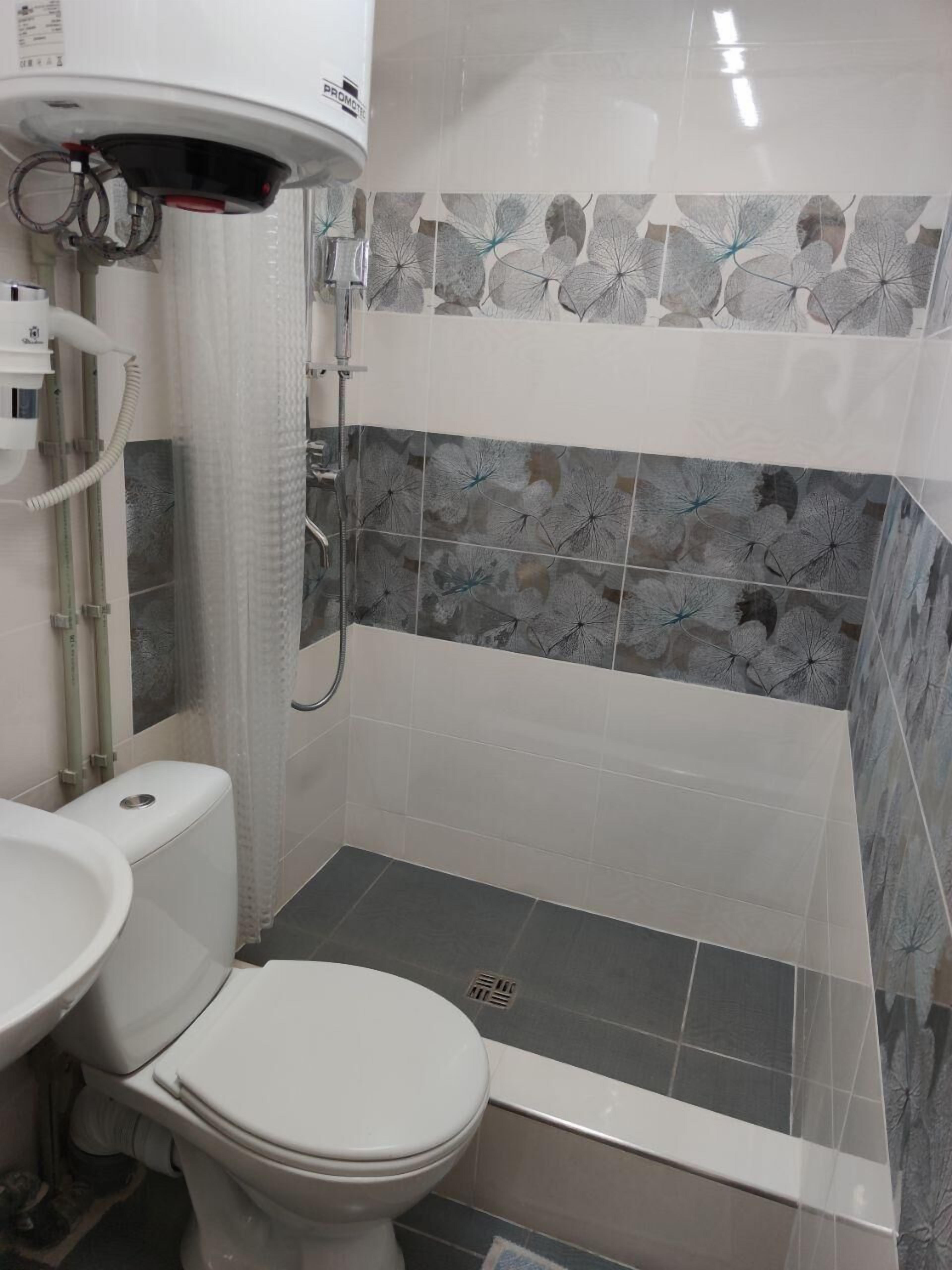 A bathroom with a toilet, a shower, and a sink.