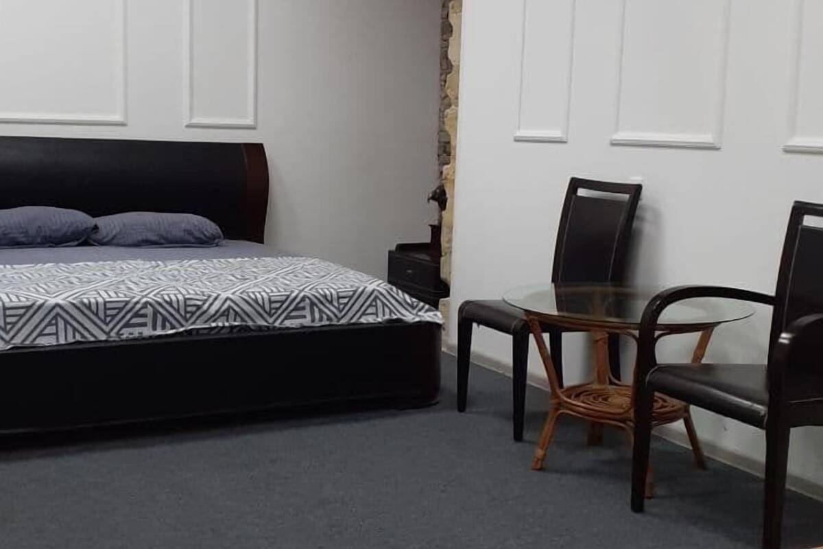 Una habitación con una cama, una mesita y dos sillas.