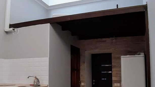 Un espacio habitable compacto con kitchenette, un baño pequeño y un tragaluz.