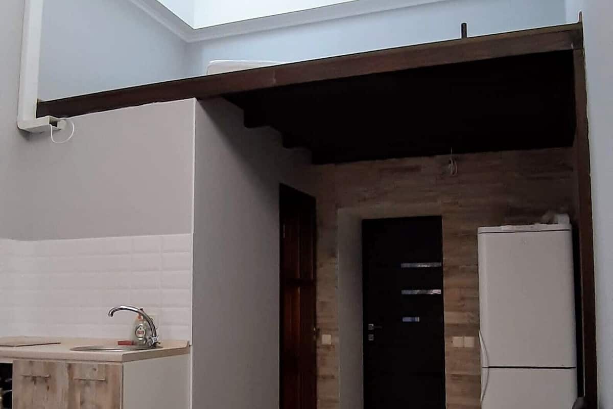 Un espacio habitable compacto con kitchenette, un baño pequeño y un tragaluz.