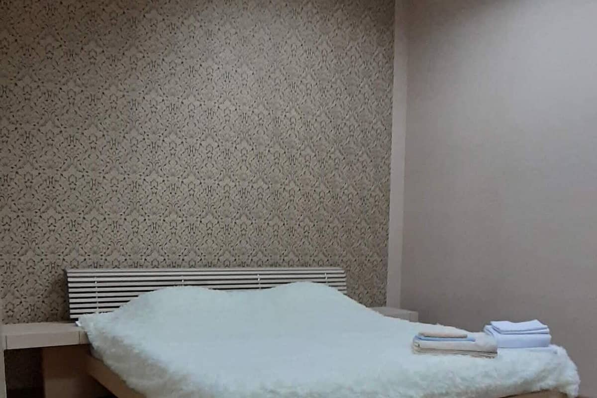 Una habitación con cama, pared con diseño y una lámpara en el techo.
